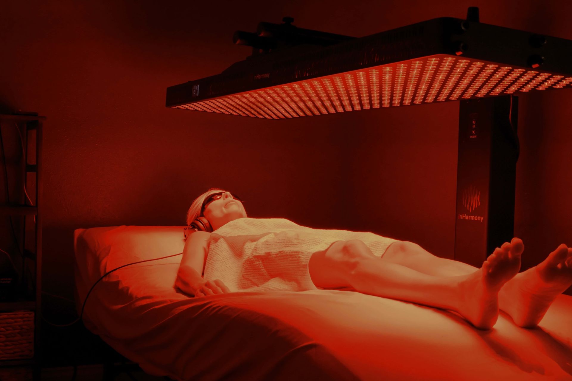 Guest on the vibroacoustic sound lounge under the glowing NIR red light panel during a Resonance Ritual at Stillness & Aesthetics Co.